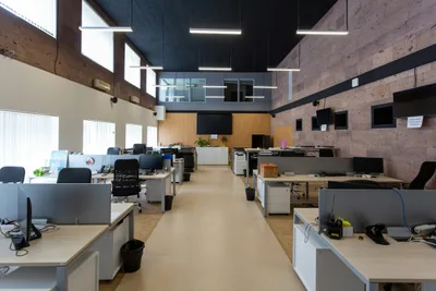 Open plan office with rows of desks over a light hard surface floor